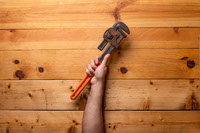 Arm holding pipe wrenches on light wooden background - Labor Day